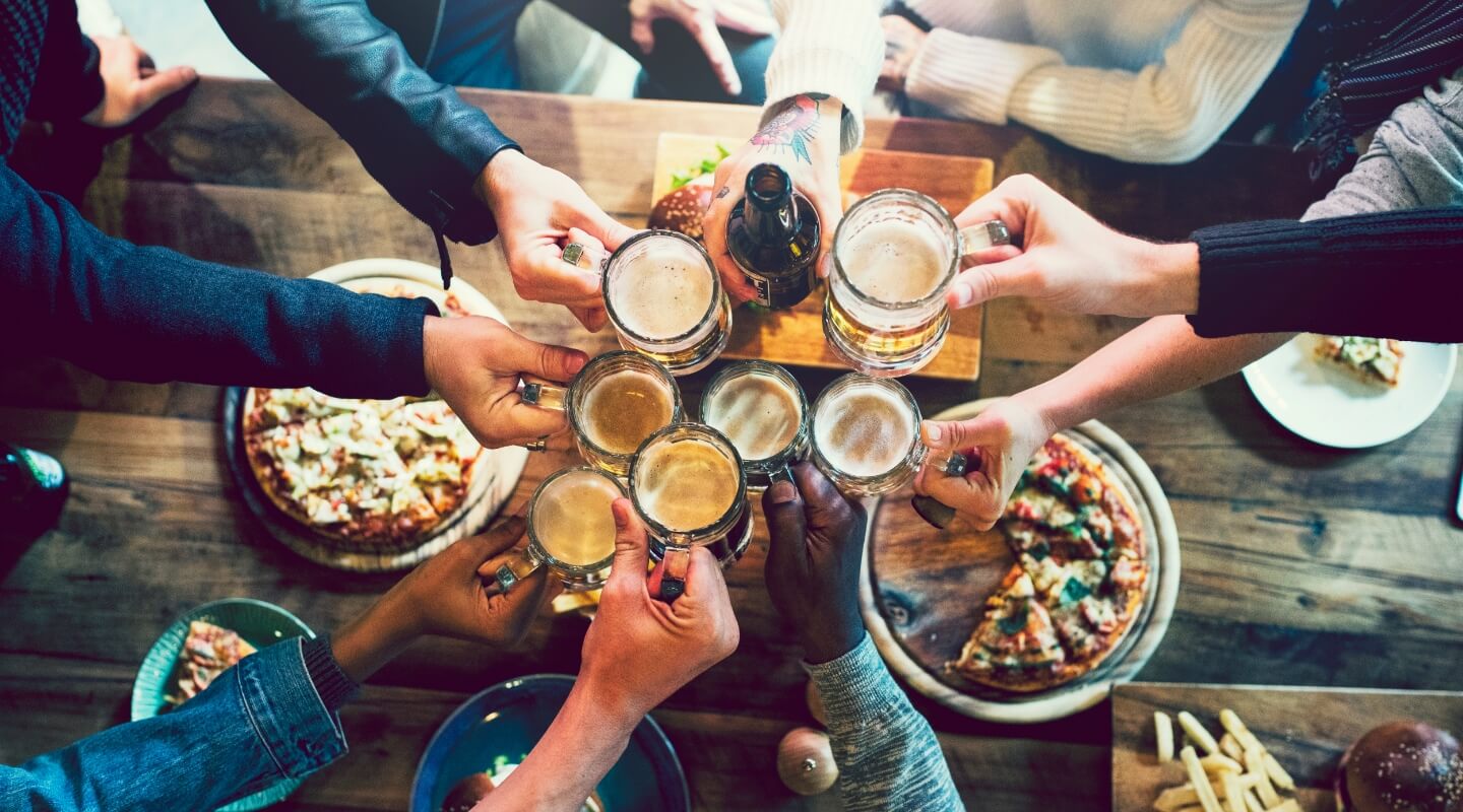 a group of young people cheersing over appetizers