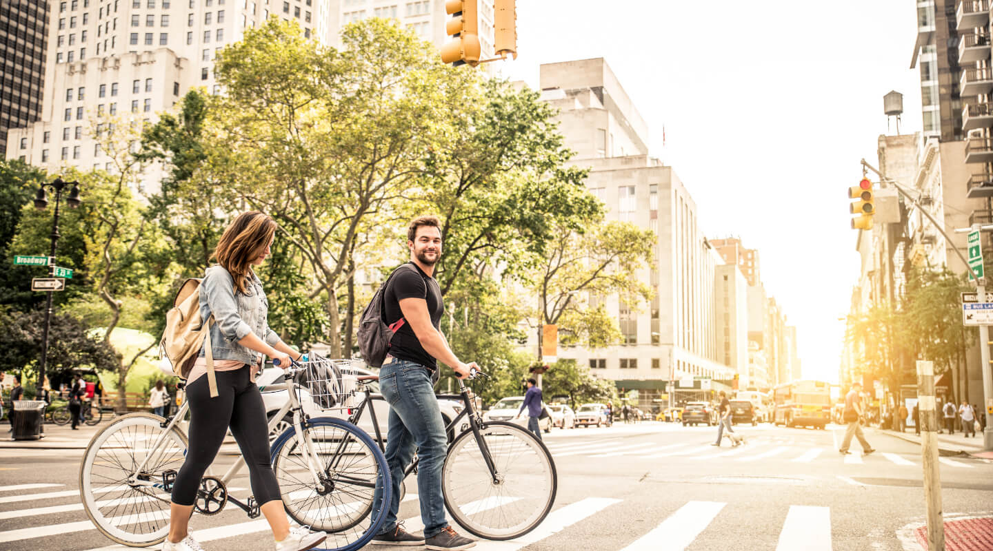 a couple walking their bikes across the street on the crosswalk