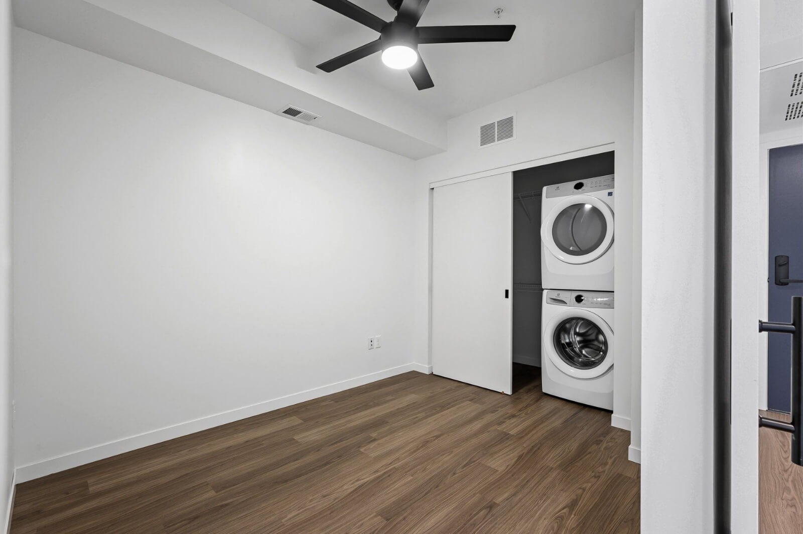 an empty apartment bedroom with a washing machine and dryer in the closet